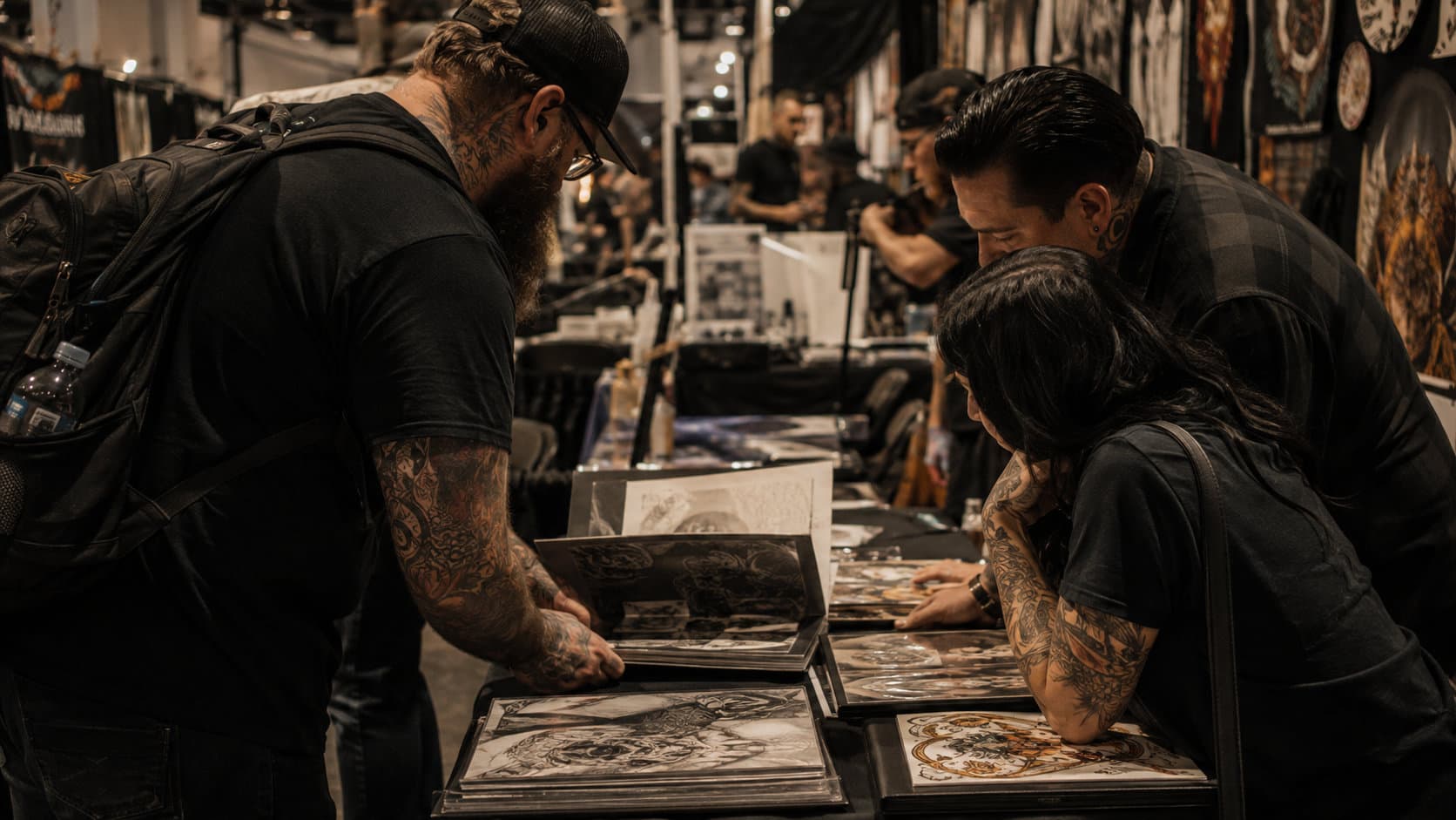 Two people looking over a tattoo portfolio at a convention table.