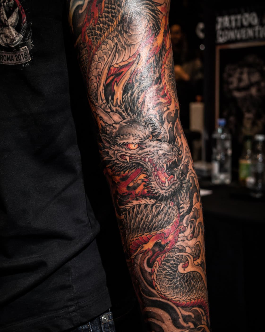 Flash-lit tattoo work on a forearm, shot on film with hard shadow.